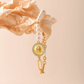 Gold bracelet with pearl accents on a beige background